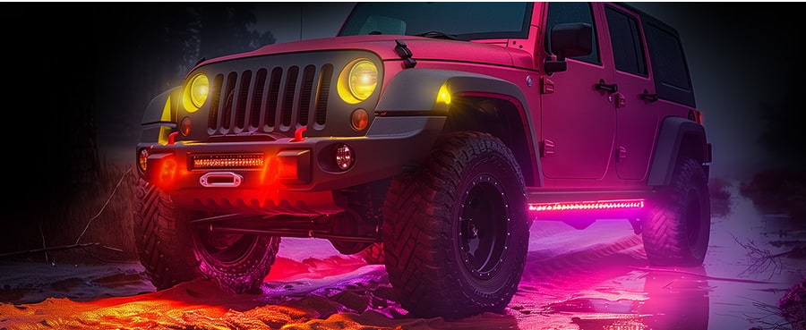 An offroad vehicle with multicolor LED underglow lights illuminating snow-covered ground at night.